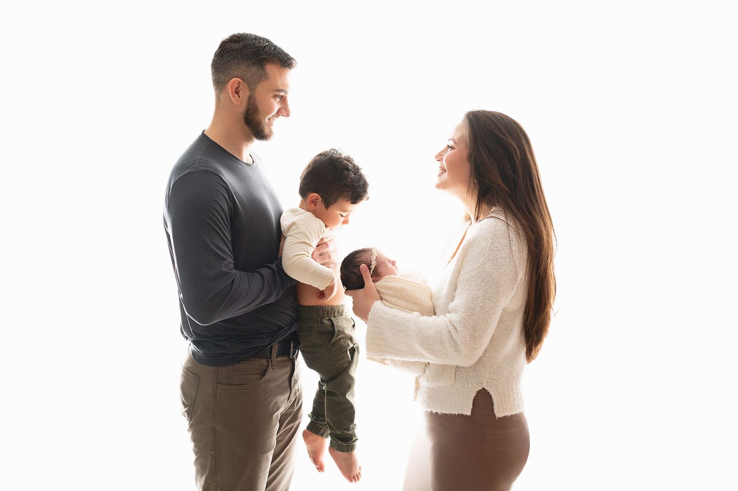 Family of three sharing joyful moment against white background in casual attire.