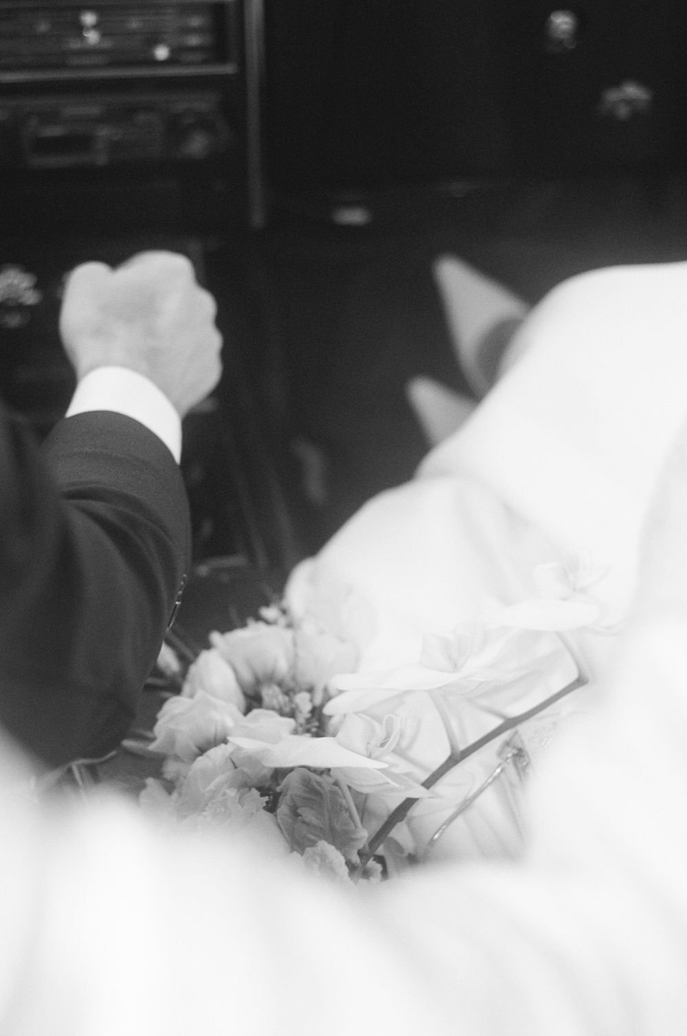 Black and white wedding photo showing bouquet details with white flowers against a dark background.
