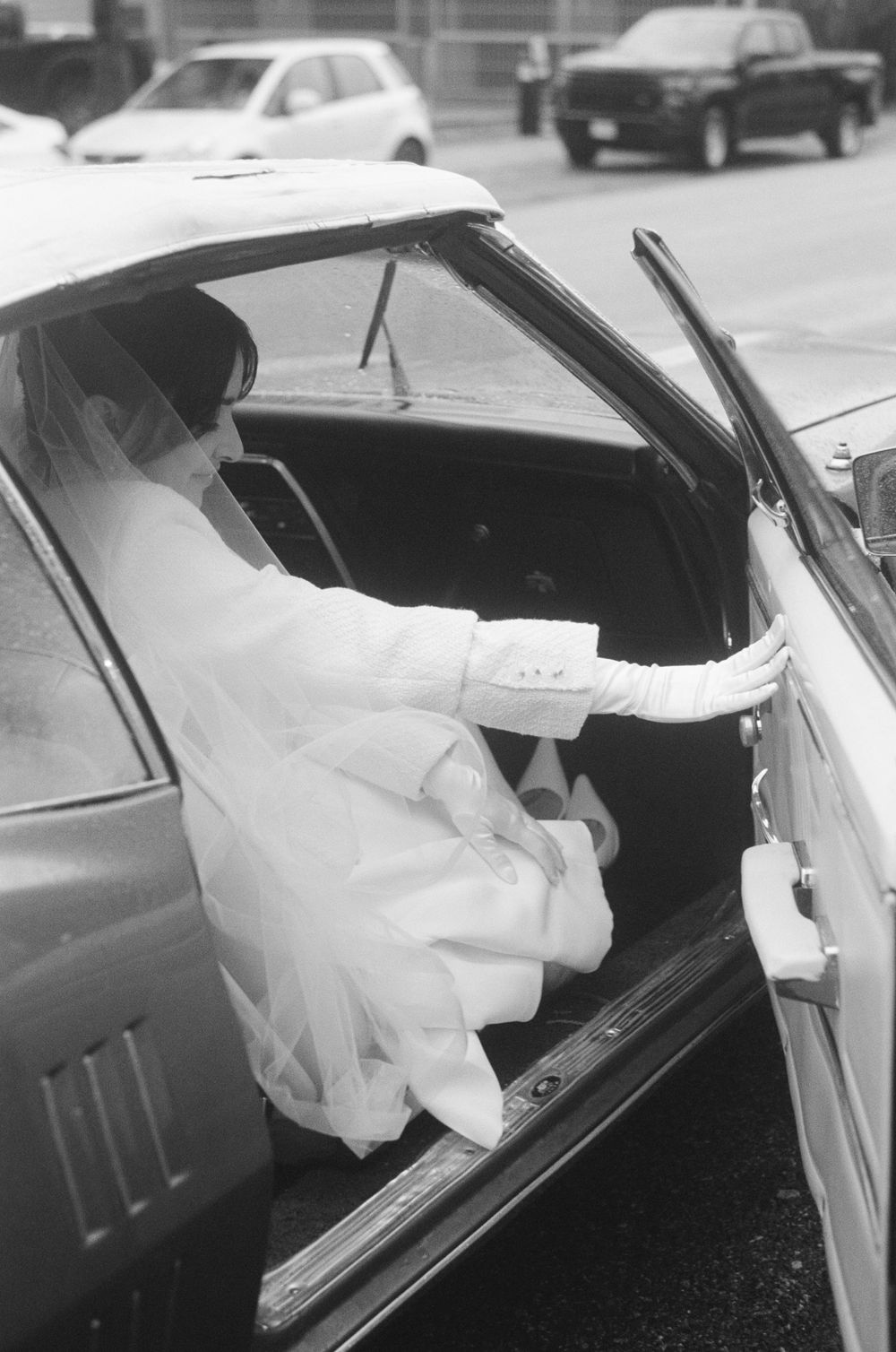 Sequence showing a bride in white dress getting into a classic car.
