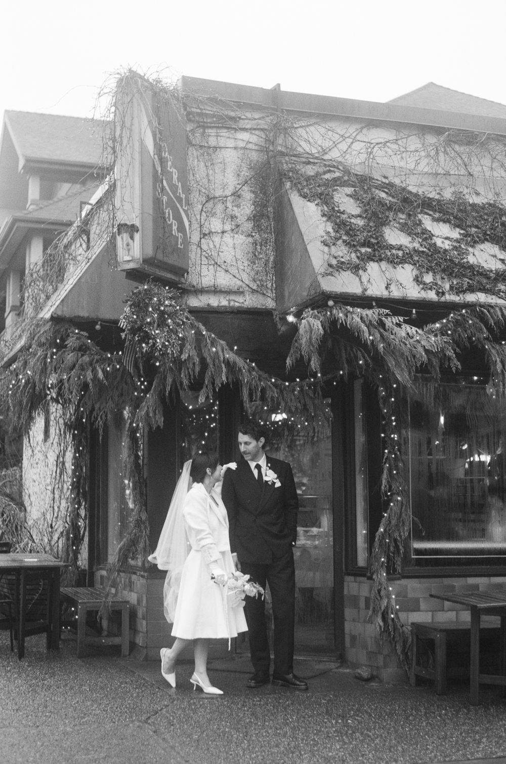 Vintage black and white photograph showing people outside a decorated storefront.