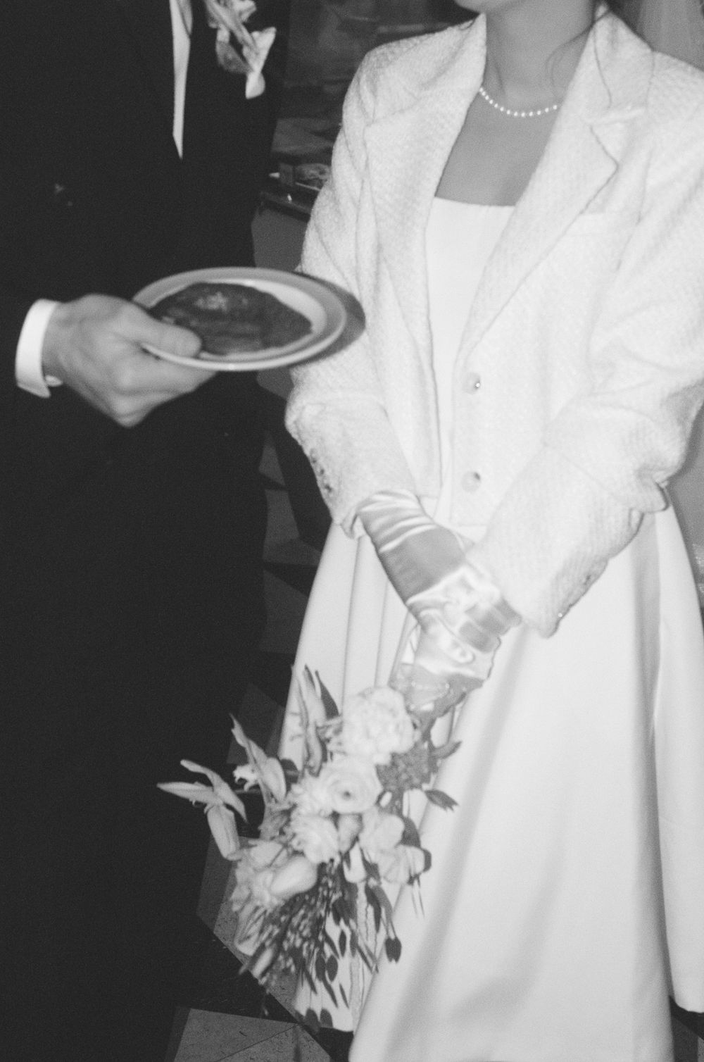 Black and white close-up of formal attire and floral bouquet details.