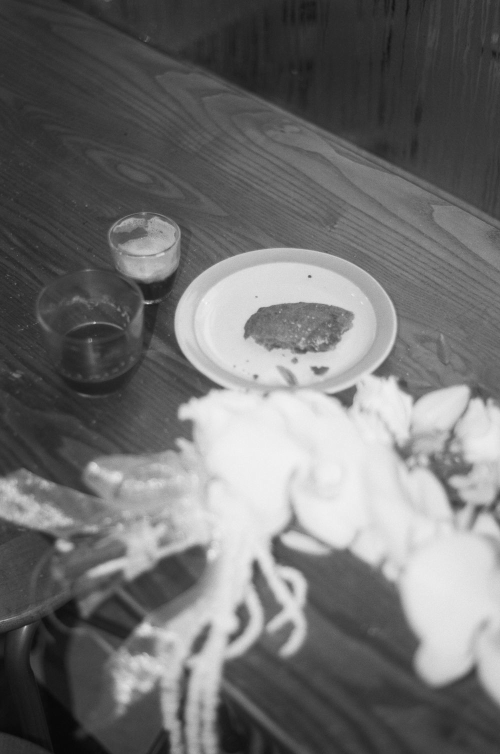 Black and white image of food and plates on a wooden table surface.
