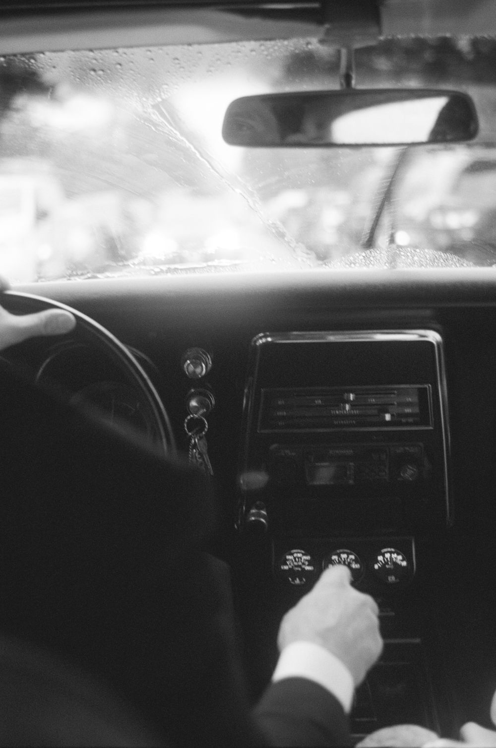 Black and white interior view of a classic car dashboard and controls.