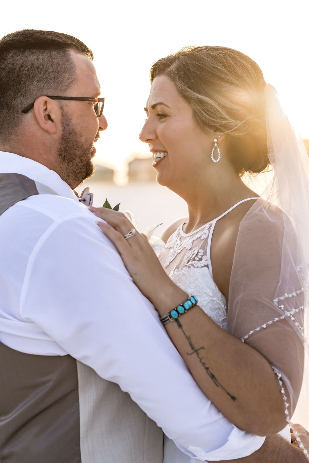 A happy couple embraces during golden hour at their wedding celebration wearing formal attire.