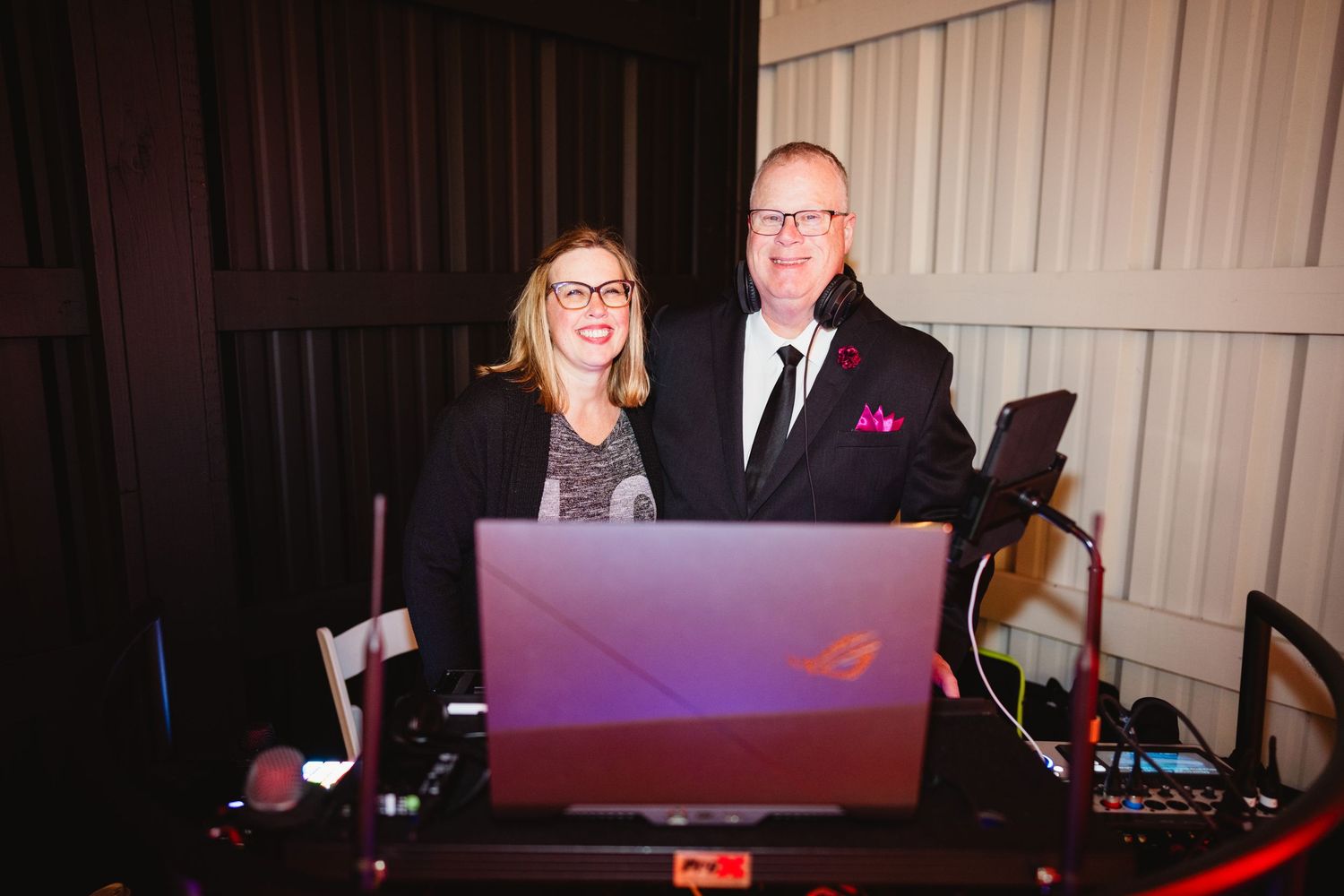 DJ setup at an event with gaming laptop and professional equipment on dark wooden table.