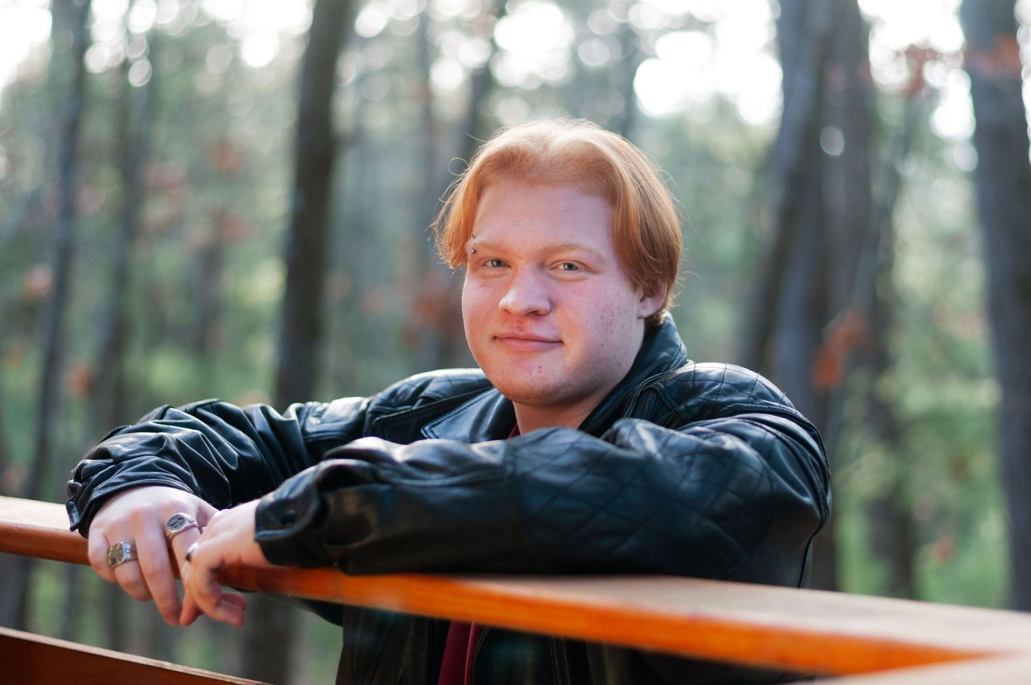 A portrait of a senior boy leaning against a railing