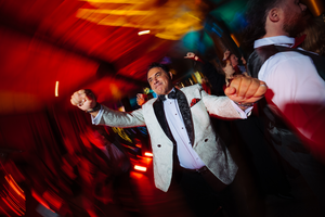 A person in formal attire performs dance moves under dramatic red lighting at a wedding reception in Lake Placid, NY.