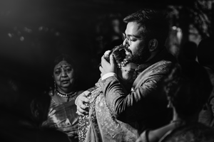 Black and white candid shot of emotional vidaai or seeing off of Indian bride post wedding.