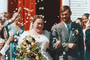 Wedding guests laugh and smile while holding champagne flutes during an outdoor celebration.