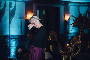 Emotional moment captured in blue-lit wedding reception venue with dramatic lighting.