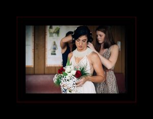 A bride in a white wedding dress holds a delicate bouquet of white and green flowers during preparation.