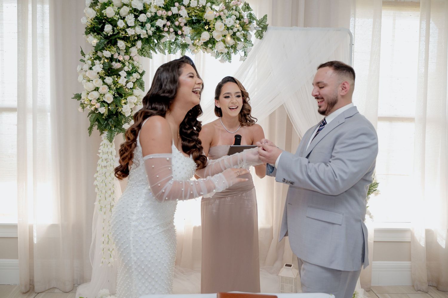 A sequence of four wedding photos showing a first look moment between newlyweds in a white floral decorated room.