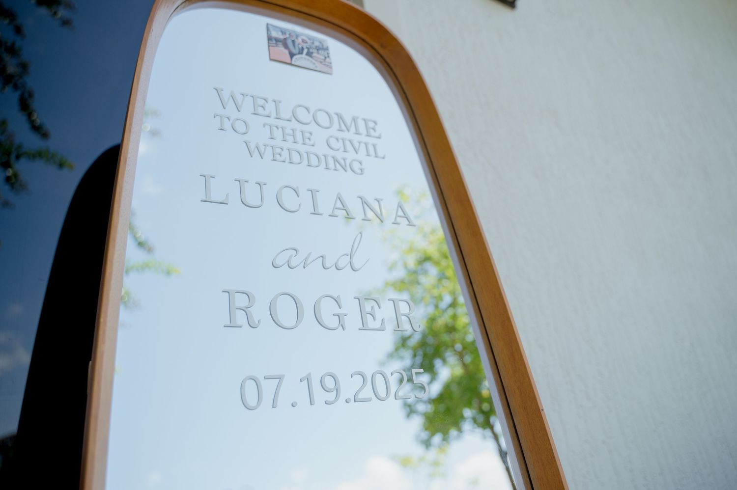 A white welcome sign on an easel displays elegant text for a wedding celebration against a light background.