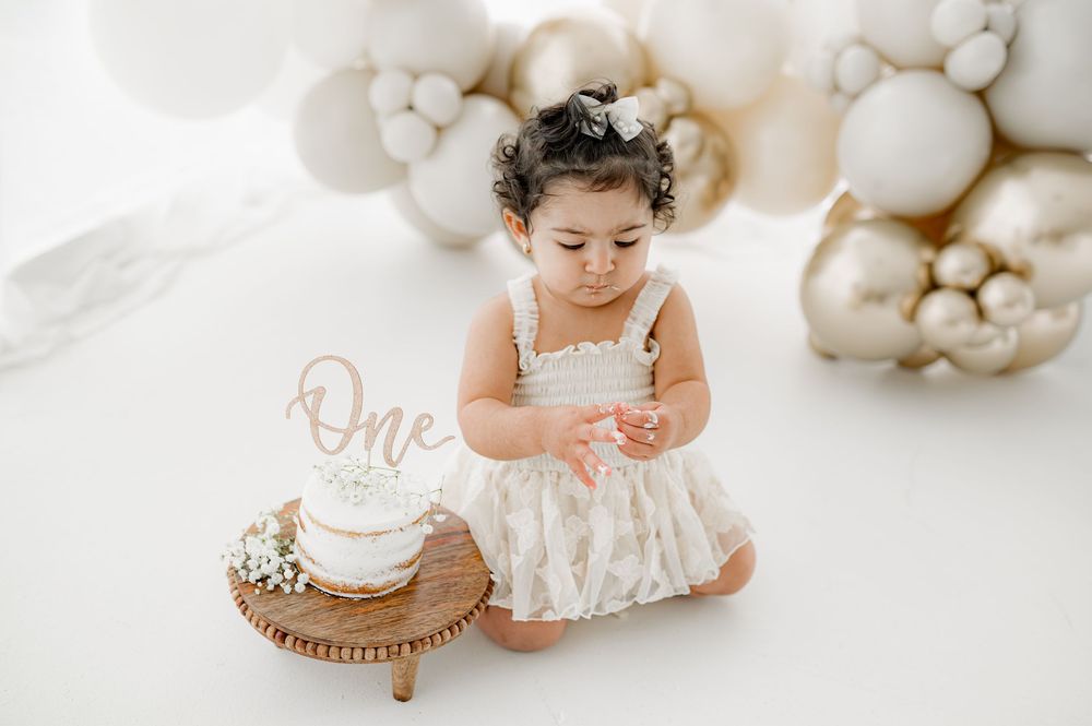 Professional baby photography session with white balloons and soft neutral tones in a studio setting.
