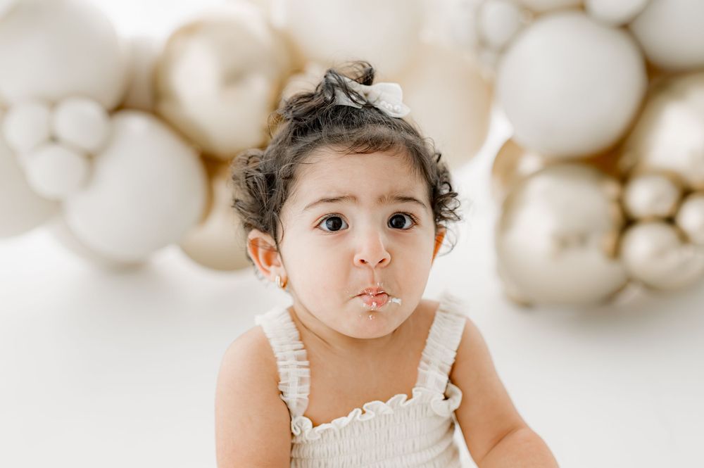 Sweet portrait with cotton-like white mushrooms forming a whimsical backdrop behind the seated subject.