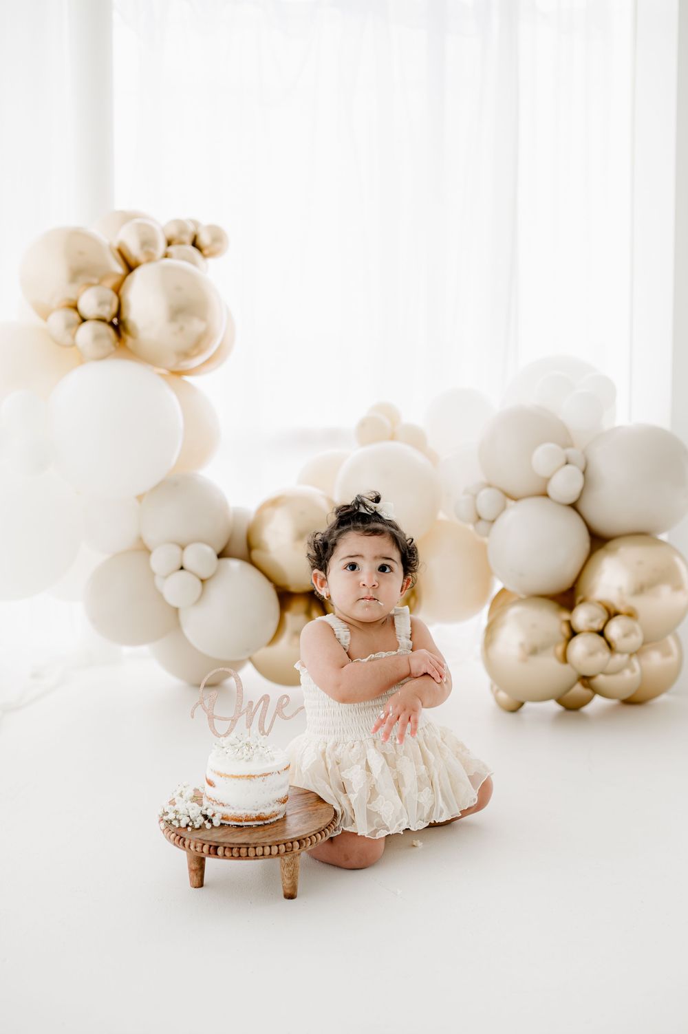 Sweet baby photo collage with white balloon garland backdrop and neutral decor in studio setting.