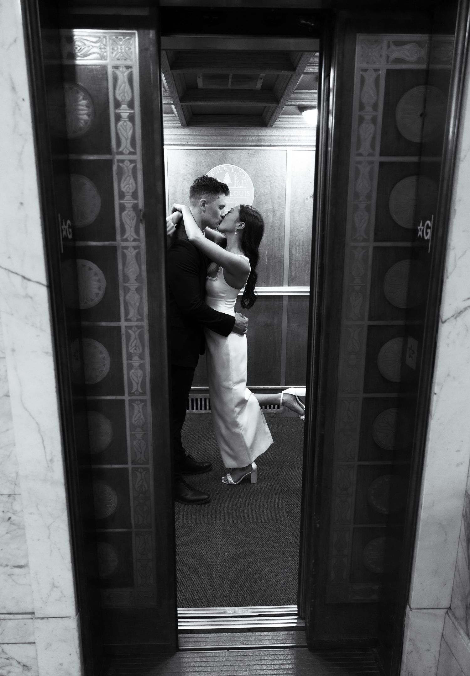 A black and white photo of subway doors closing with passengers boarding at a station platform.