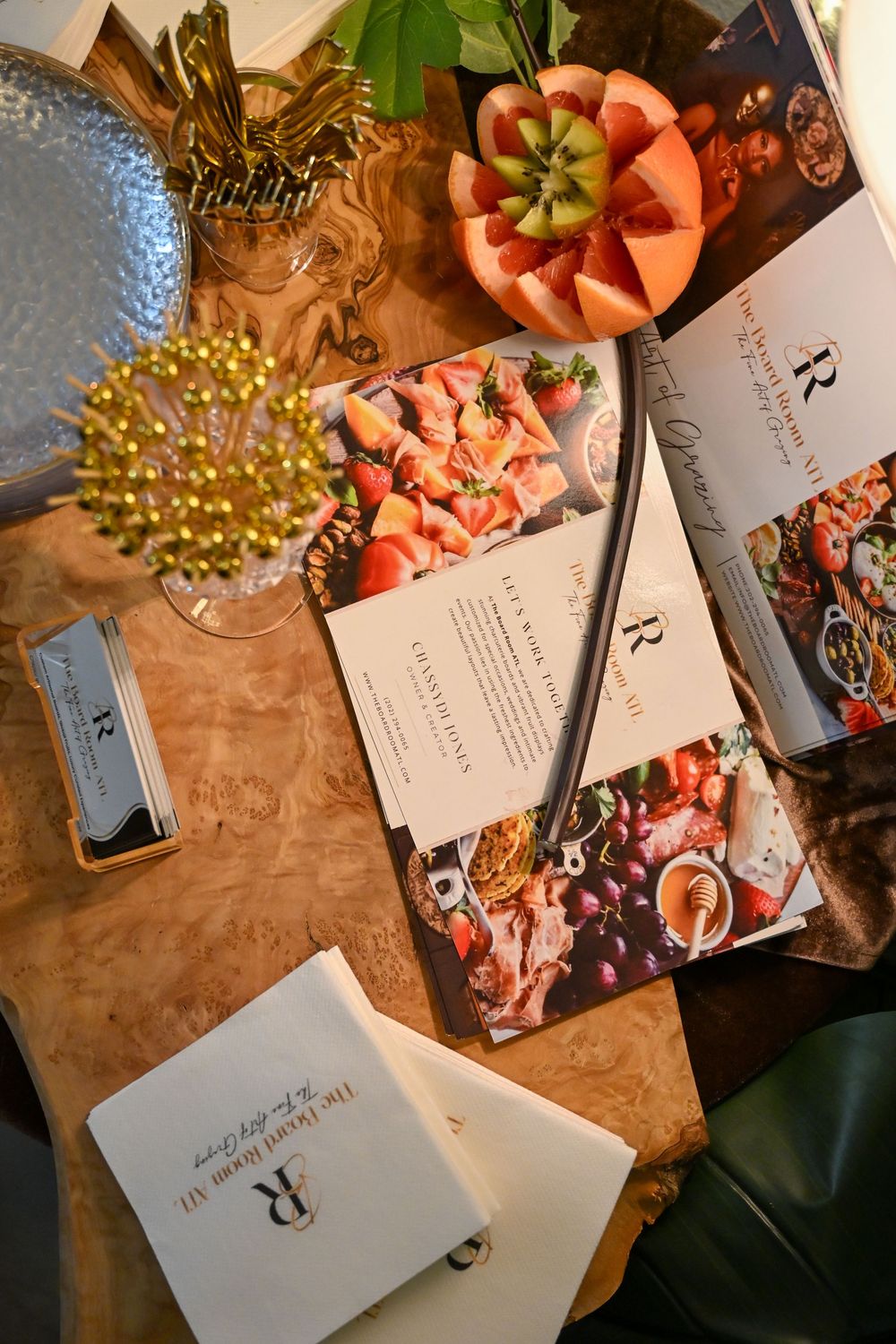 Closeup of table settings with coral flowers, invitation cards and golden decorative elements at an elegant event.