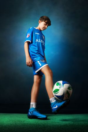 Young soccer player in blue uniform practices ball control skills.