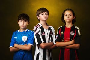 Youth soccer players lined up wearing different team jerseys against yellow background.