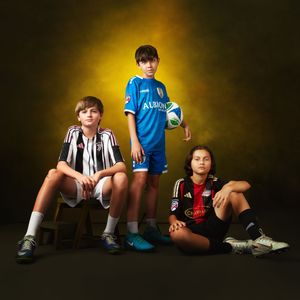 Youth soccer players sitting on ground with balls against dramatic yellow backdrop.