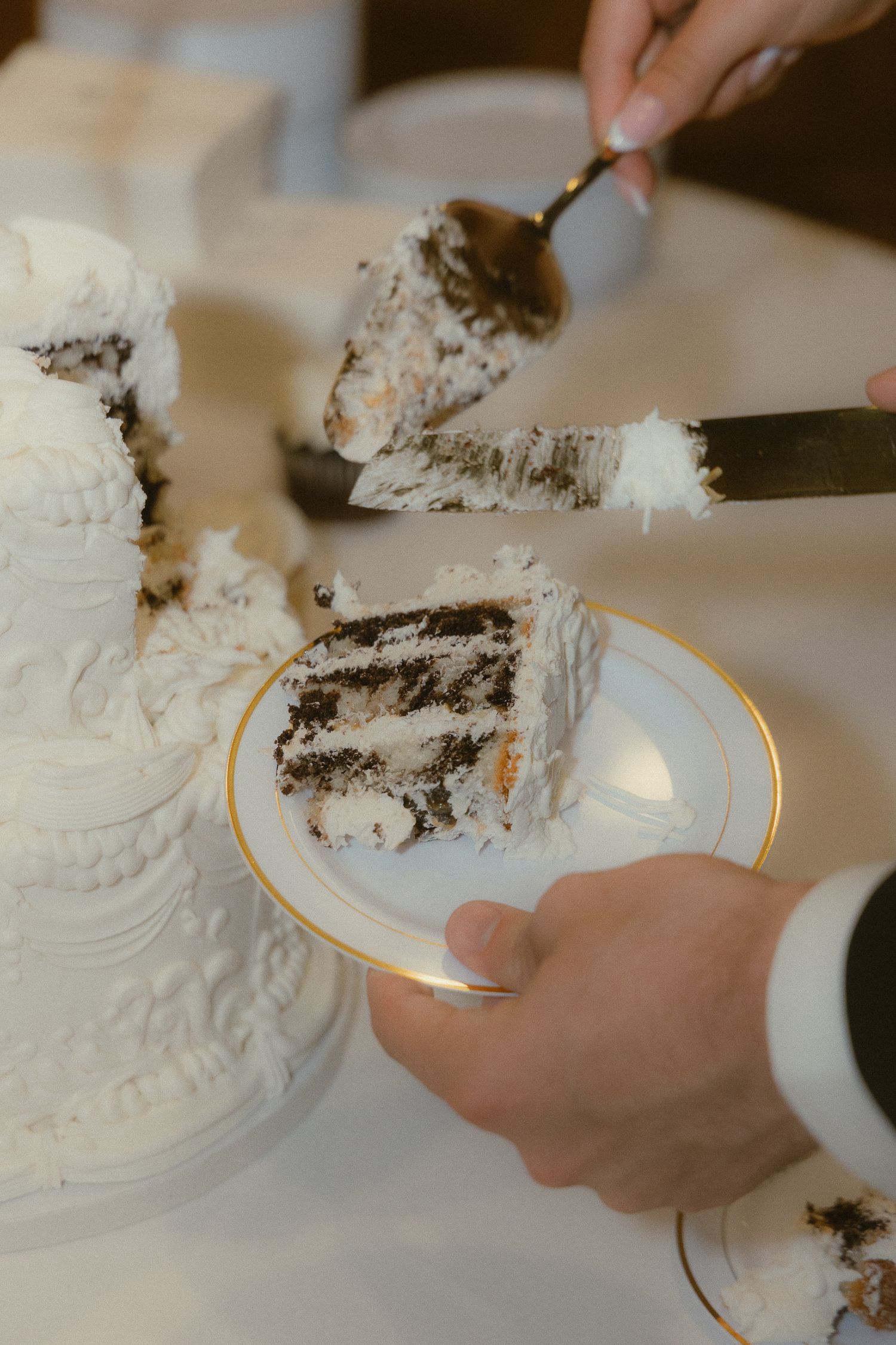 Close-up details of hands holding and touching a white lace wedding dress in romantic lighting.