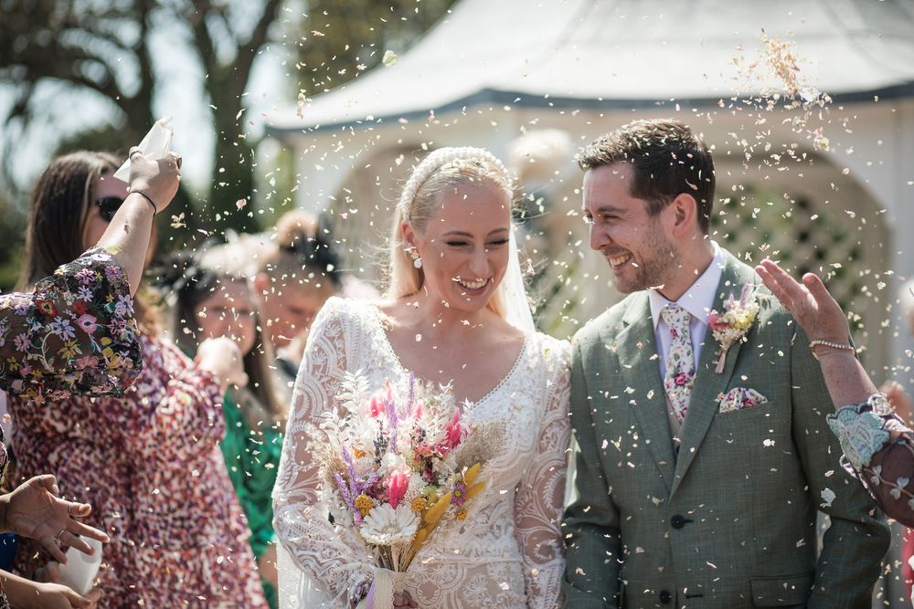 Wedding couple surrounded by confetti and celebration during an outdoor ceremony.