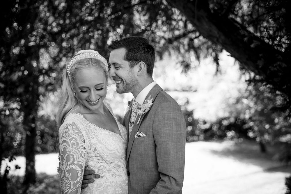 Black and white portrait of newlyweds sharing an intimate moment in a garden setting.