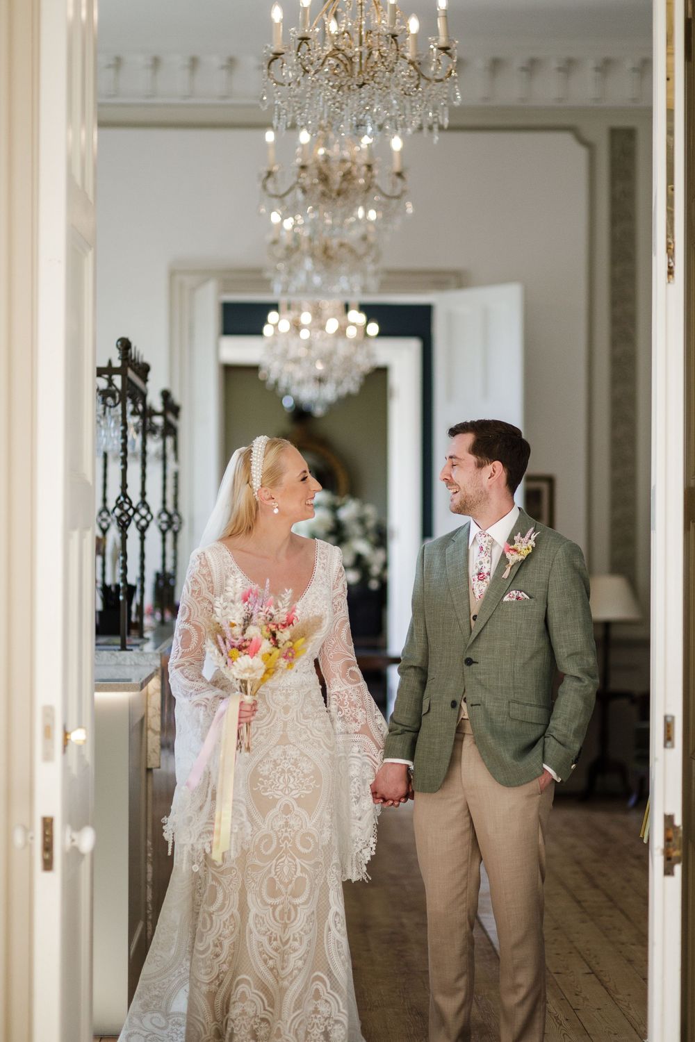 Elegant white room with chandeliers serves as backdrop for romantic wedding portraits.