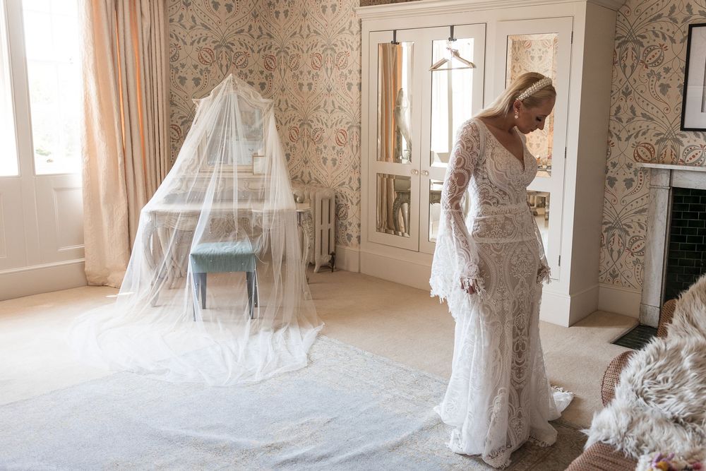 Bridal preparations in a vintage-styled room with floral wallpaper and flowing white veil.