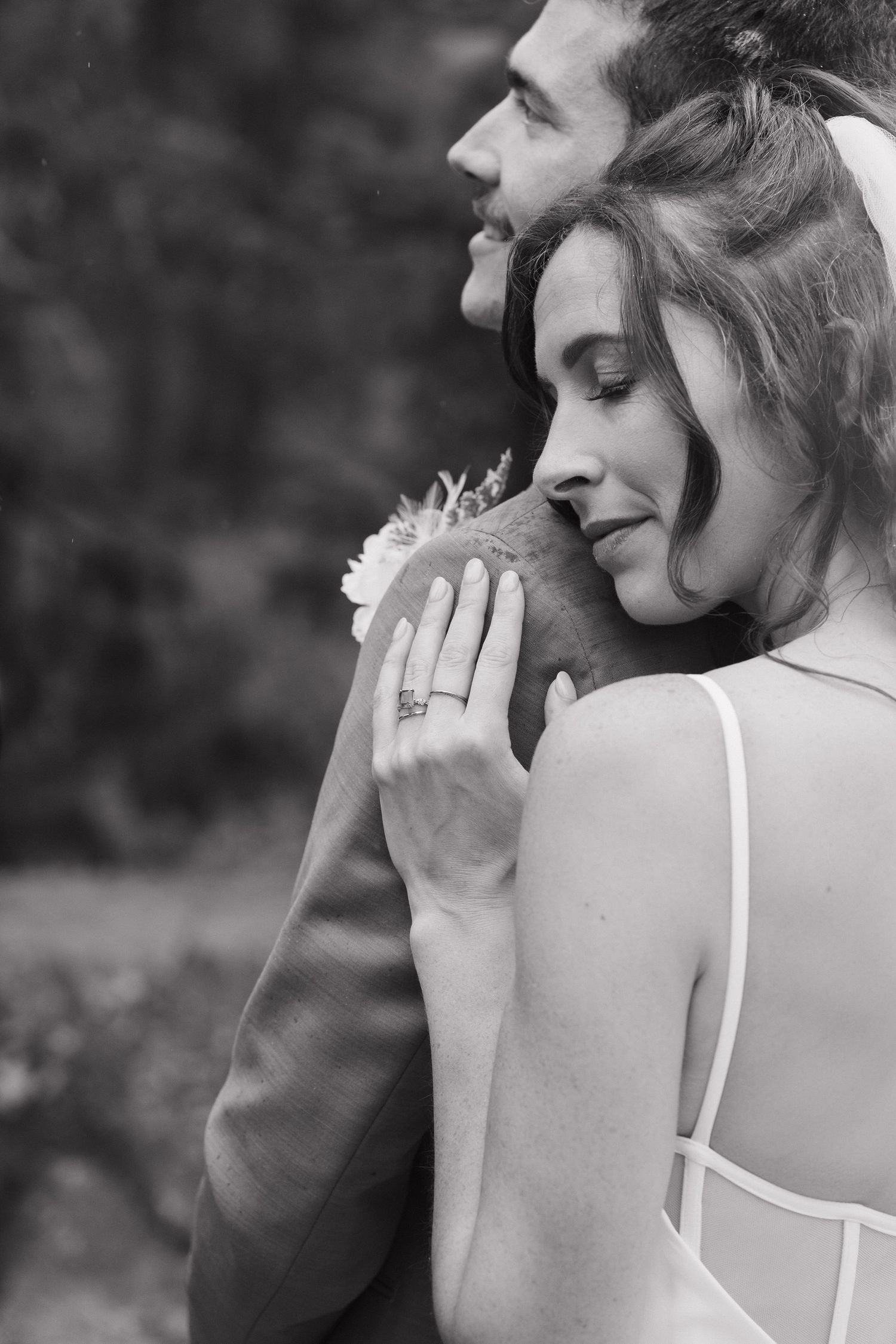 An intimate black and white wedding portrait showing a tender embrace and engagement ring.