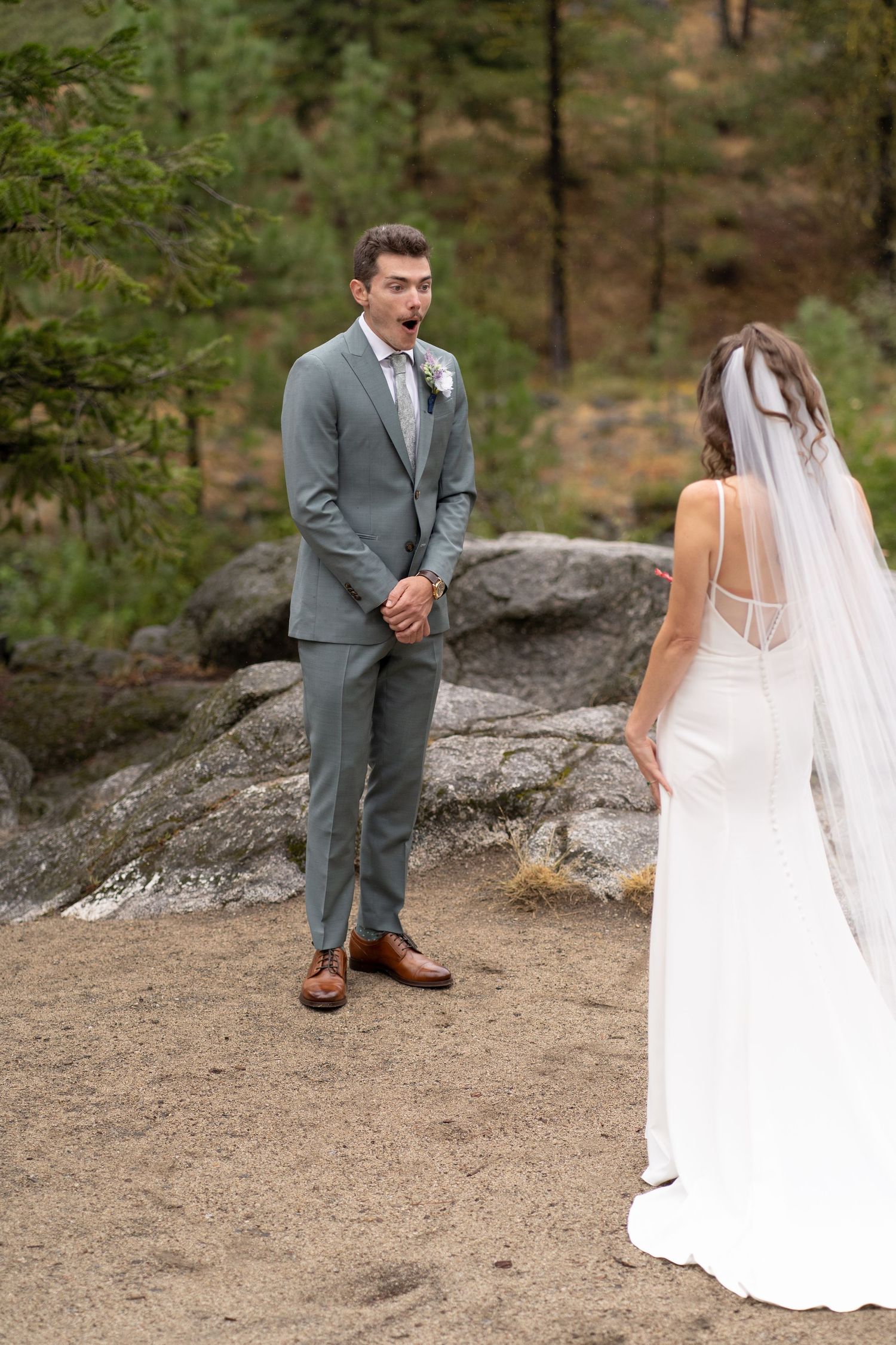 A rustic outdoor wedding first look moment captured between newlyweds on rocky terrain.