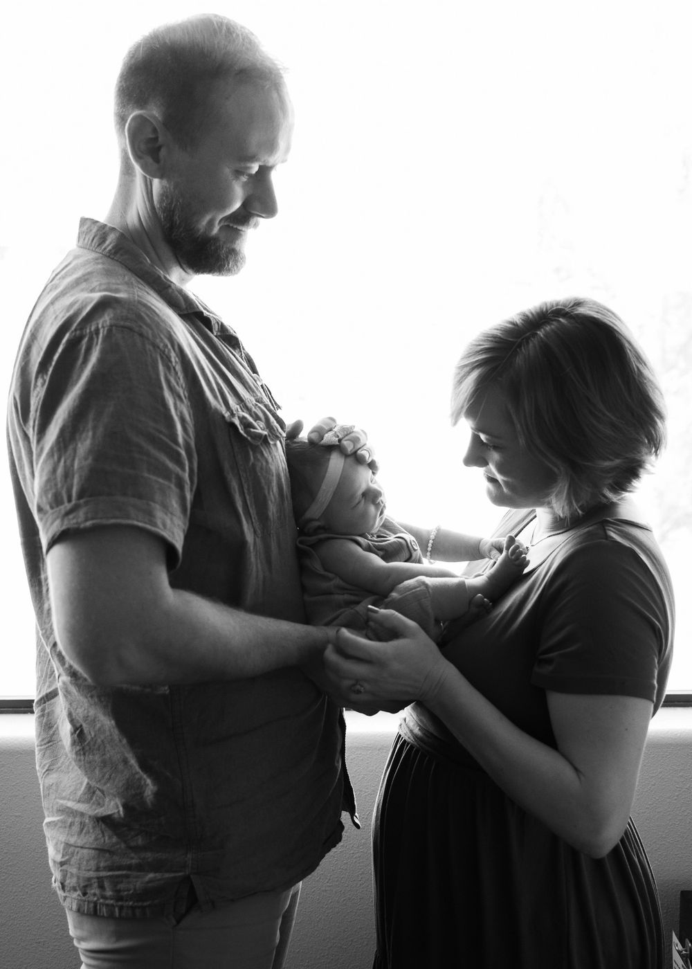black and white silhouette of mom and dad holding newborn baby