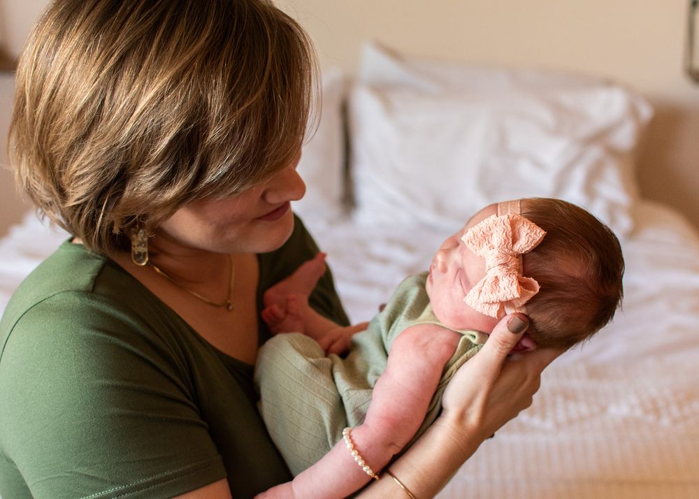 mom looking lovingly at newborn baby on bed