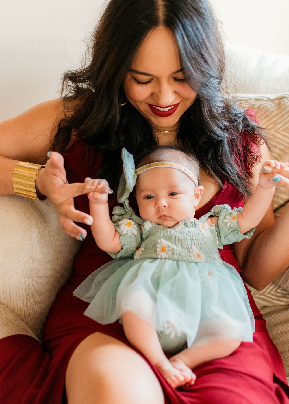 mom holding newborn daughter in her lap holding hands
