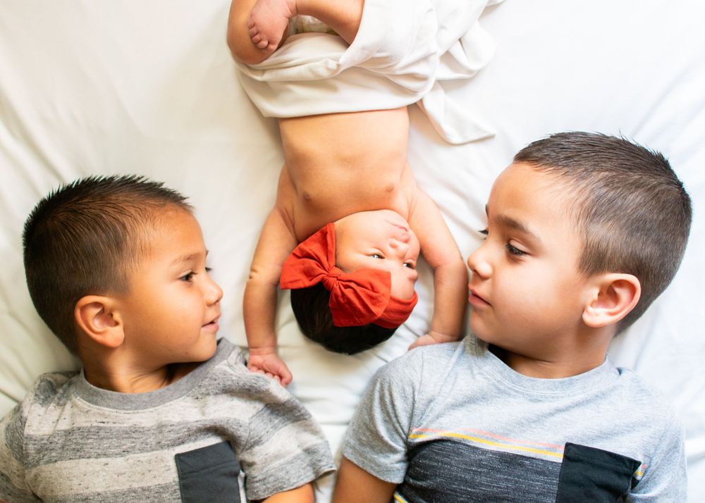 sibling photo with baby sister lying down