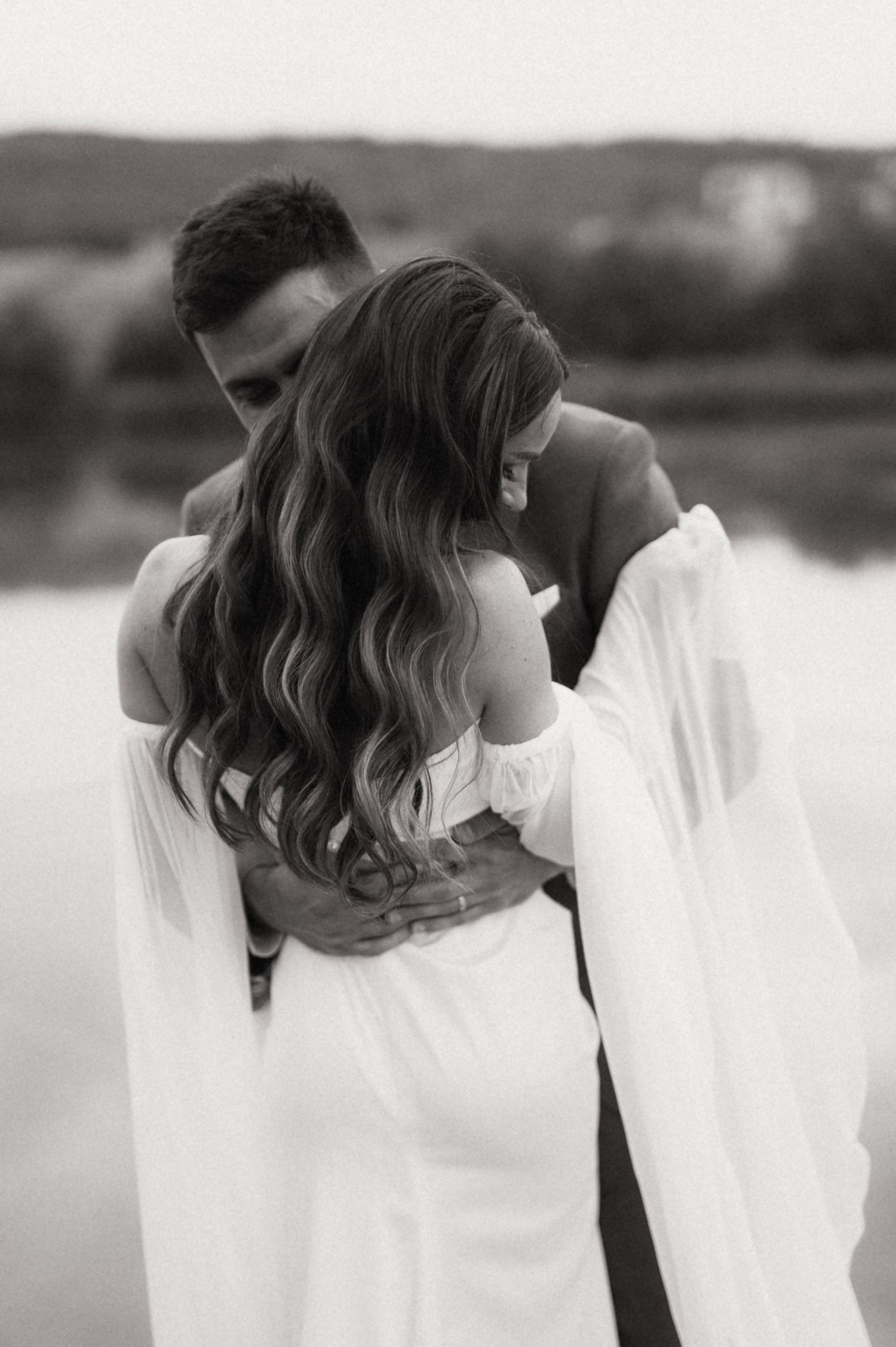 Black and white artistic wedding portrait showing a couple in an intimate moment with flowing fabric.