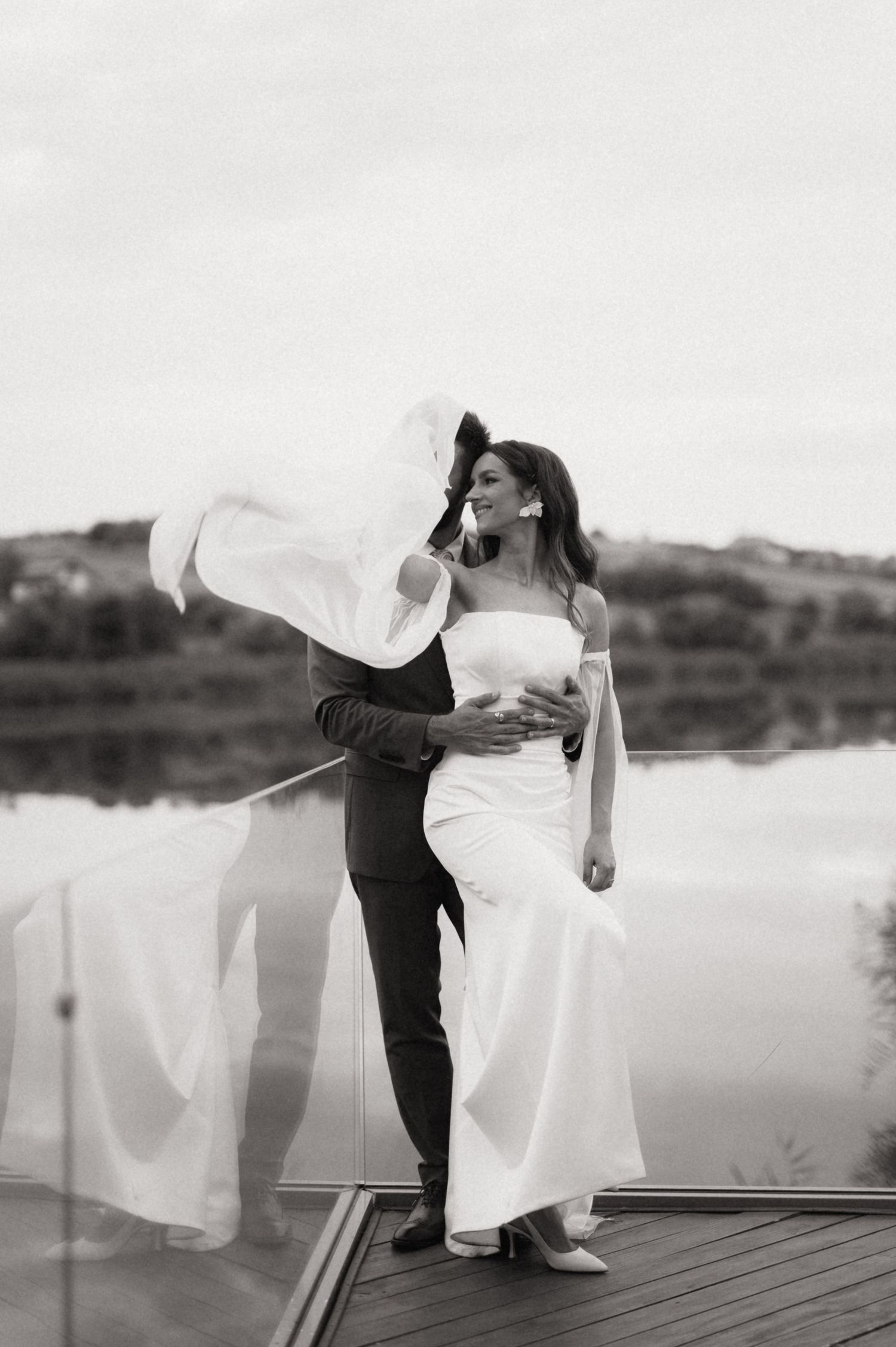 A romantic black and white wedding photo sequence showing a couple dancing on a lakeside dock at sunset.