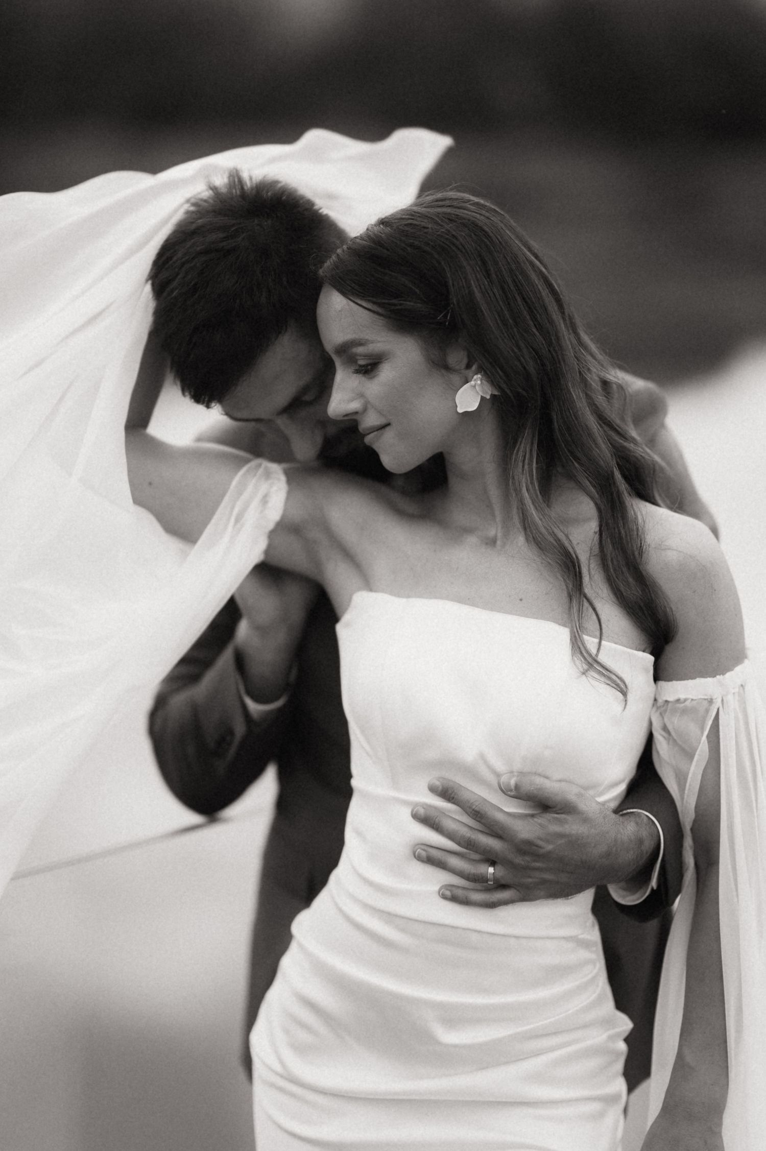 A romantic black and white photo series showing tender moments between newlyweds with flowing veil.