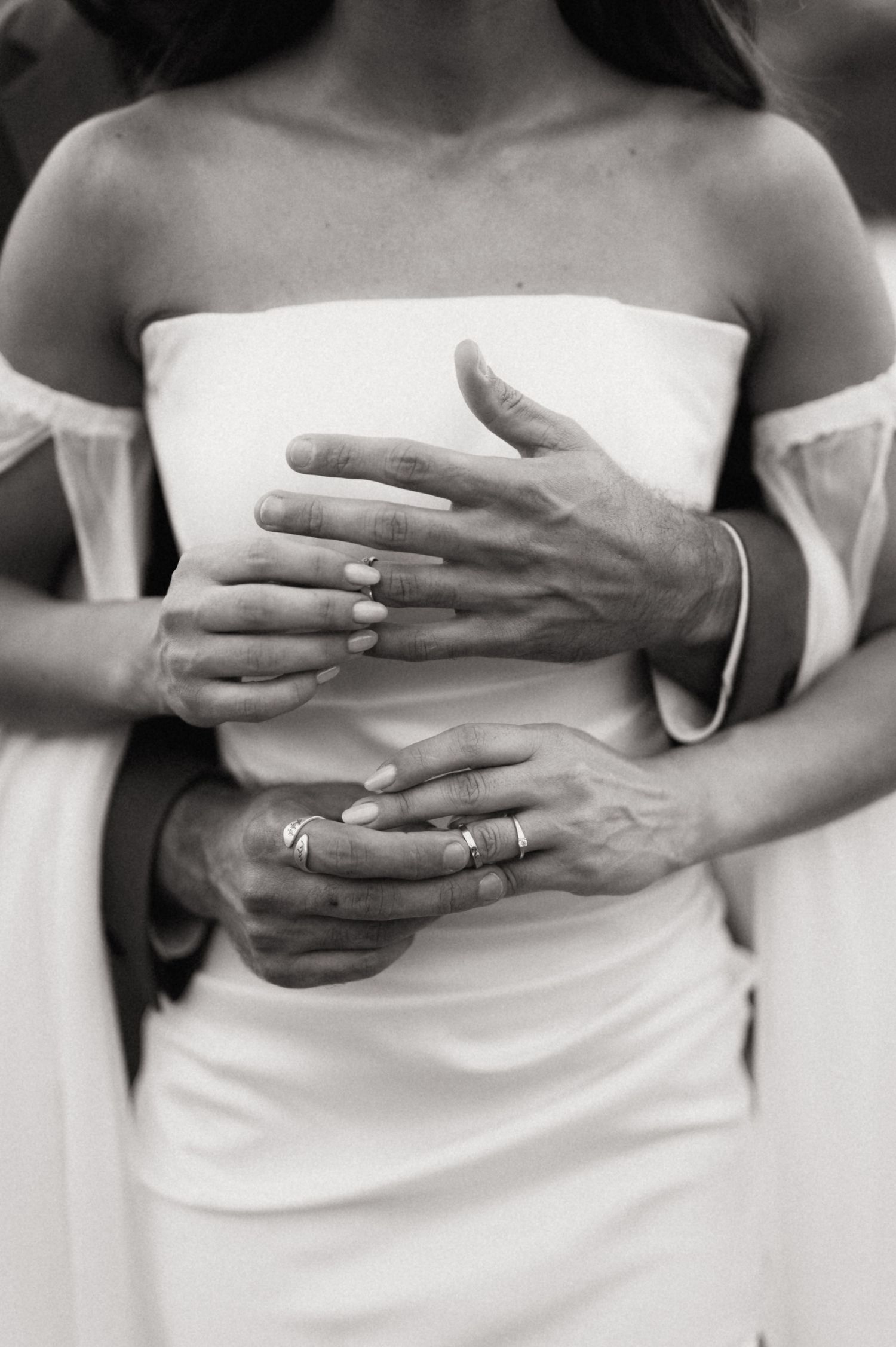 A series of black and white close-up photos showing hands with wedding rings resting against white fabric.