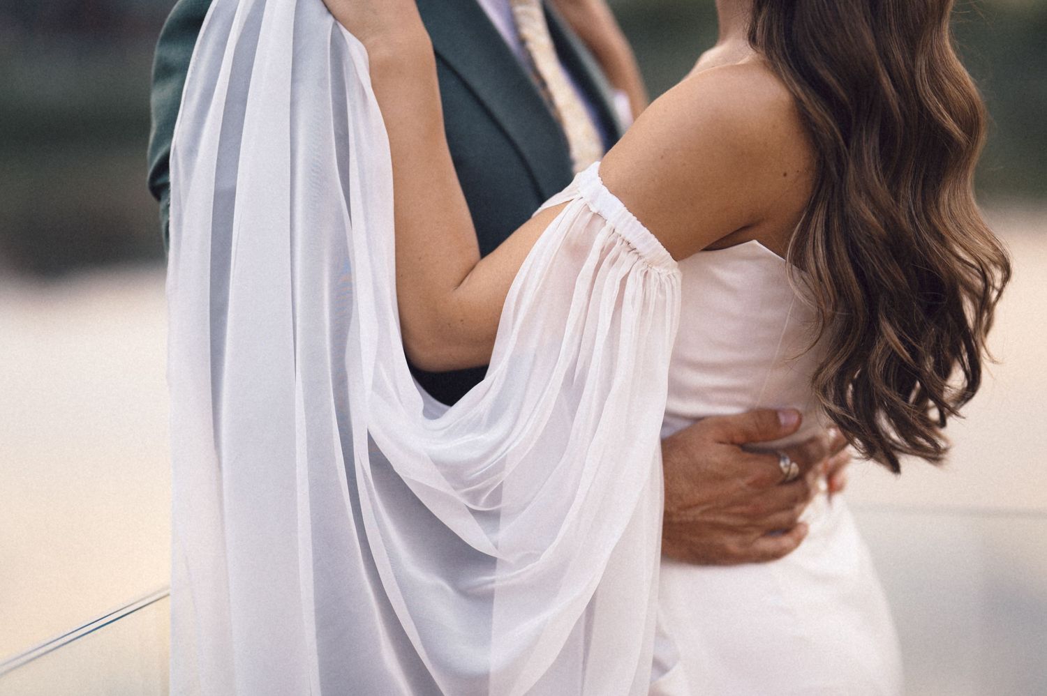 A romantic wedding moment showing the flowing white dress and gentle embrace of a couple.