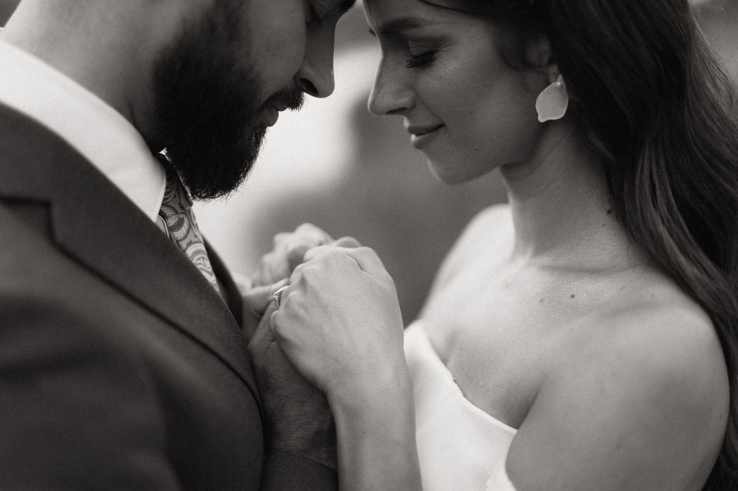 An intimate black and white portrait of a couple sharing a tender moment in wedding attire.