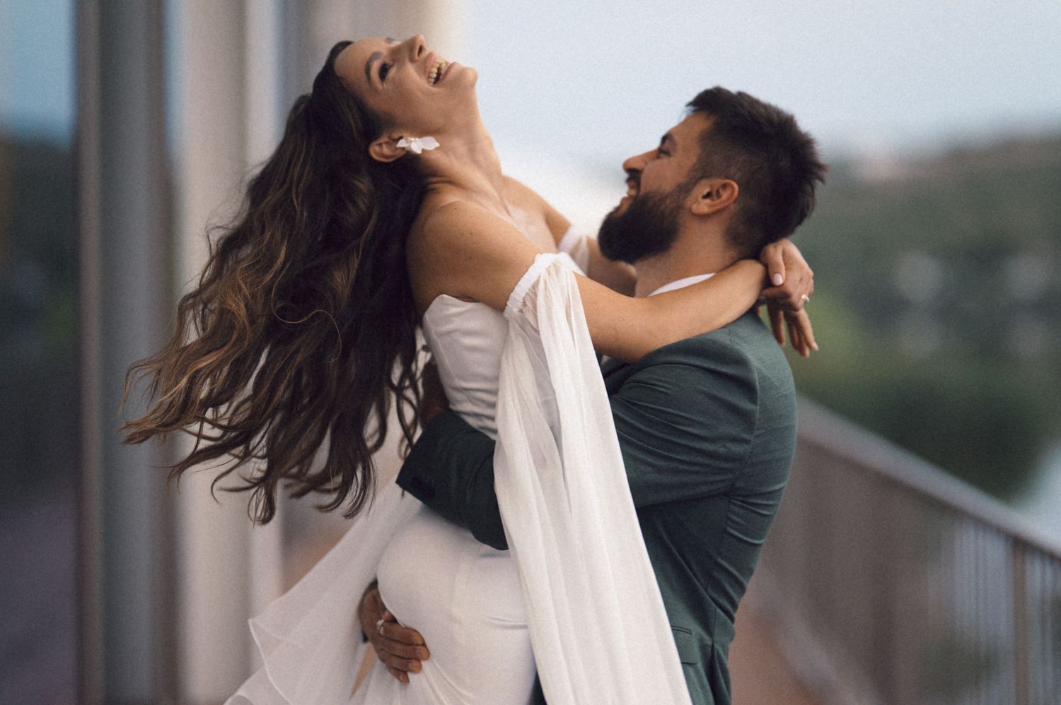 A couple in romantic poses on a balcony during their engagement photoshoot at sunset.