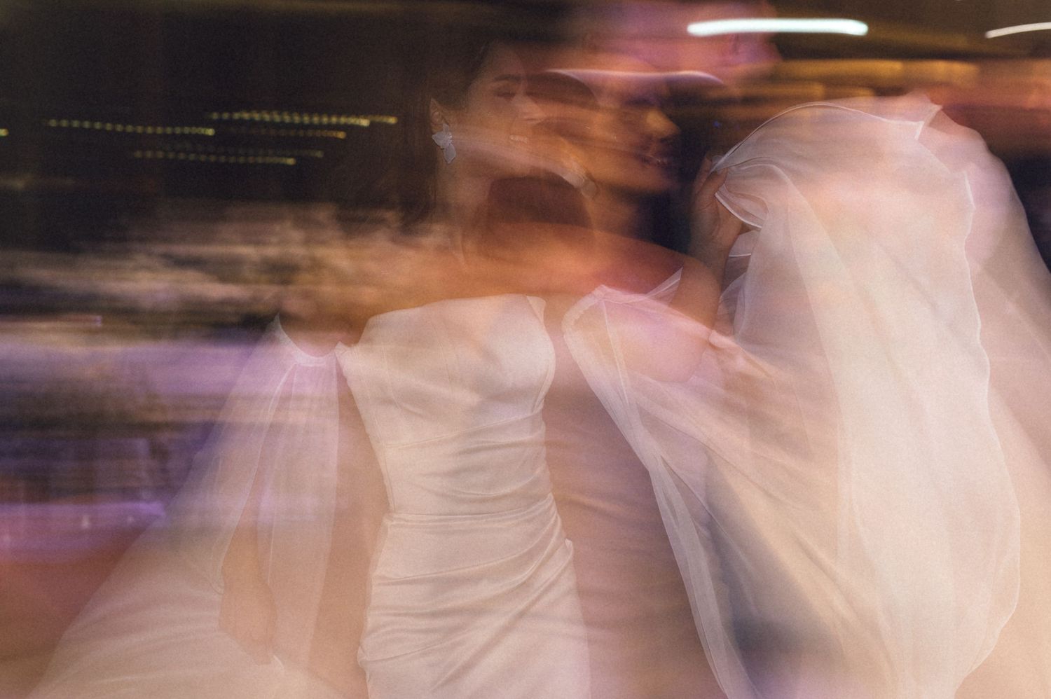 Long exposure photograph of a dance performance creates ethereal motion blur effect on stage.