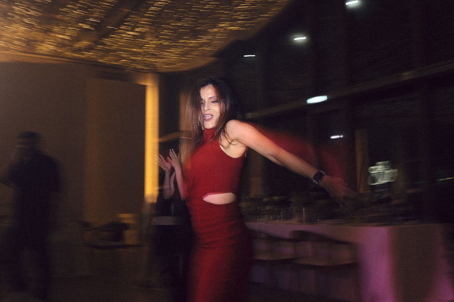 A person in a red dress dances gracefully in a dimly lit room with atmospheric lighting.