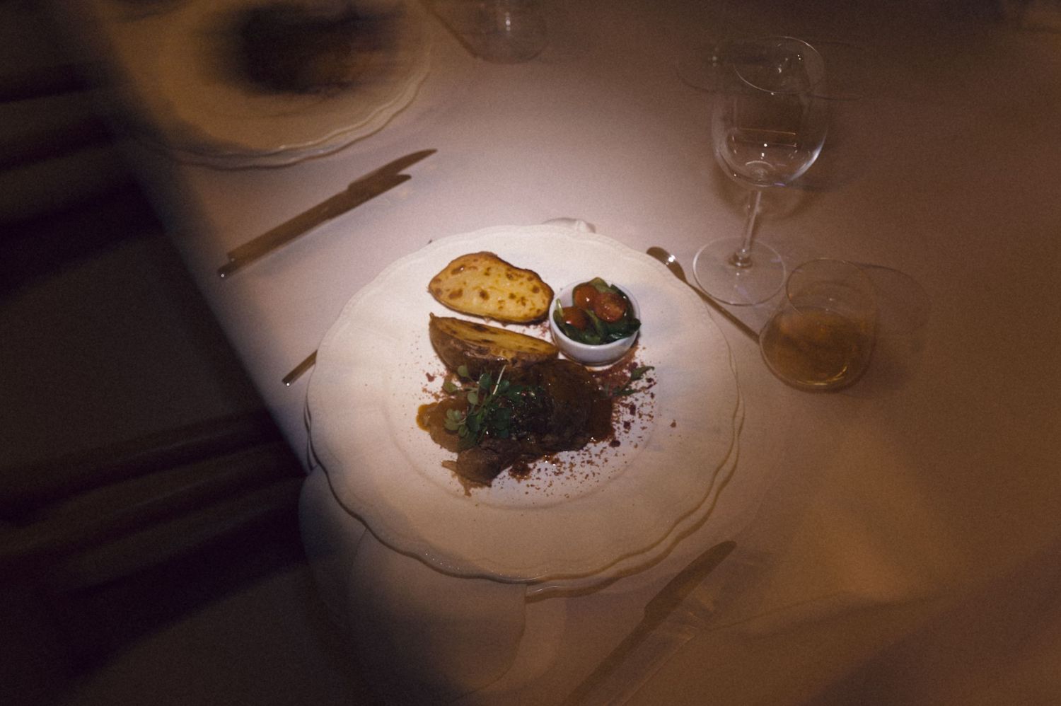 Elegant plated dessert with chocolate sauce and garnish on a white plate in dramatic lighting.