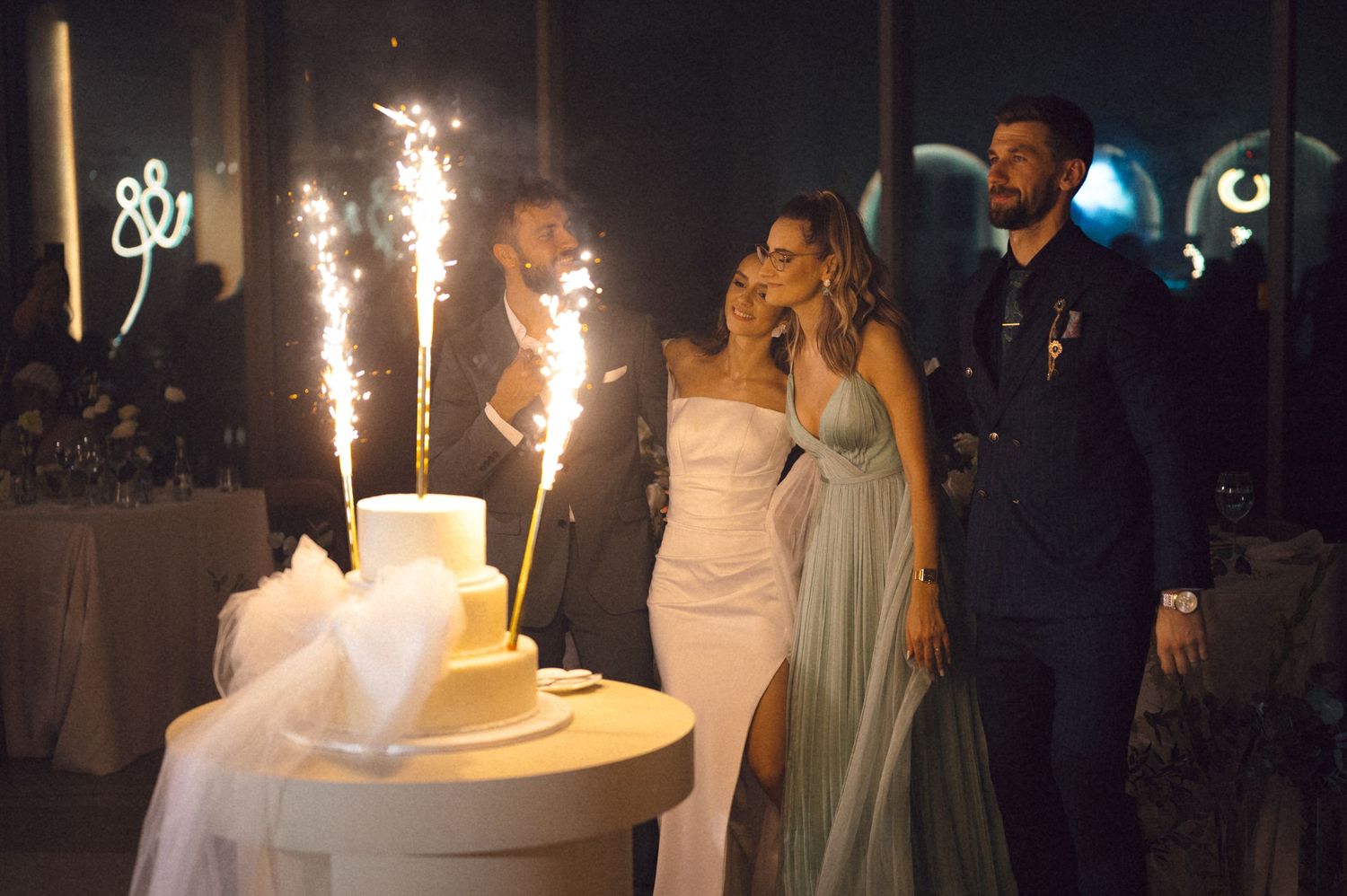 Wedding couple and guests celebrate with sparklers during an elegant outdoor evening reception celebration.