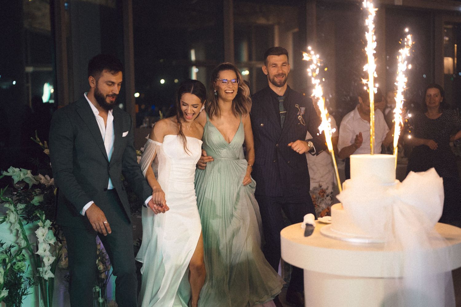 Wedding celebration with sparklers illuminating the night as guests gather around a wedding cake.