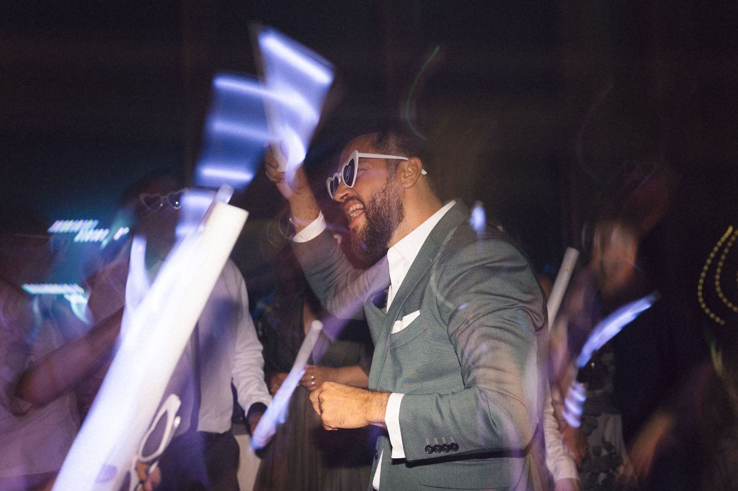 A performer in a grey suit sings passionately on stage with blue lighting effects in the background.