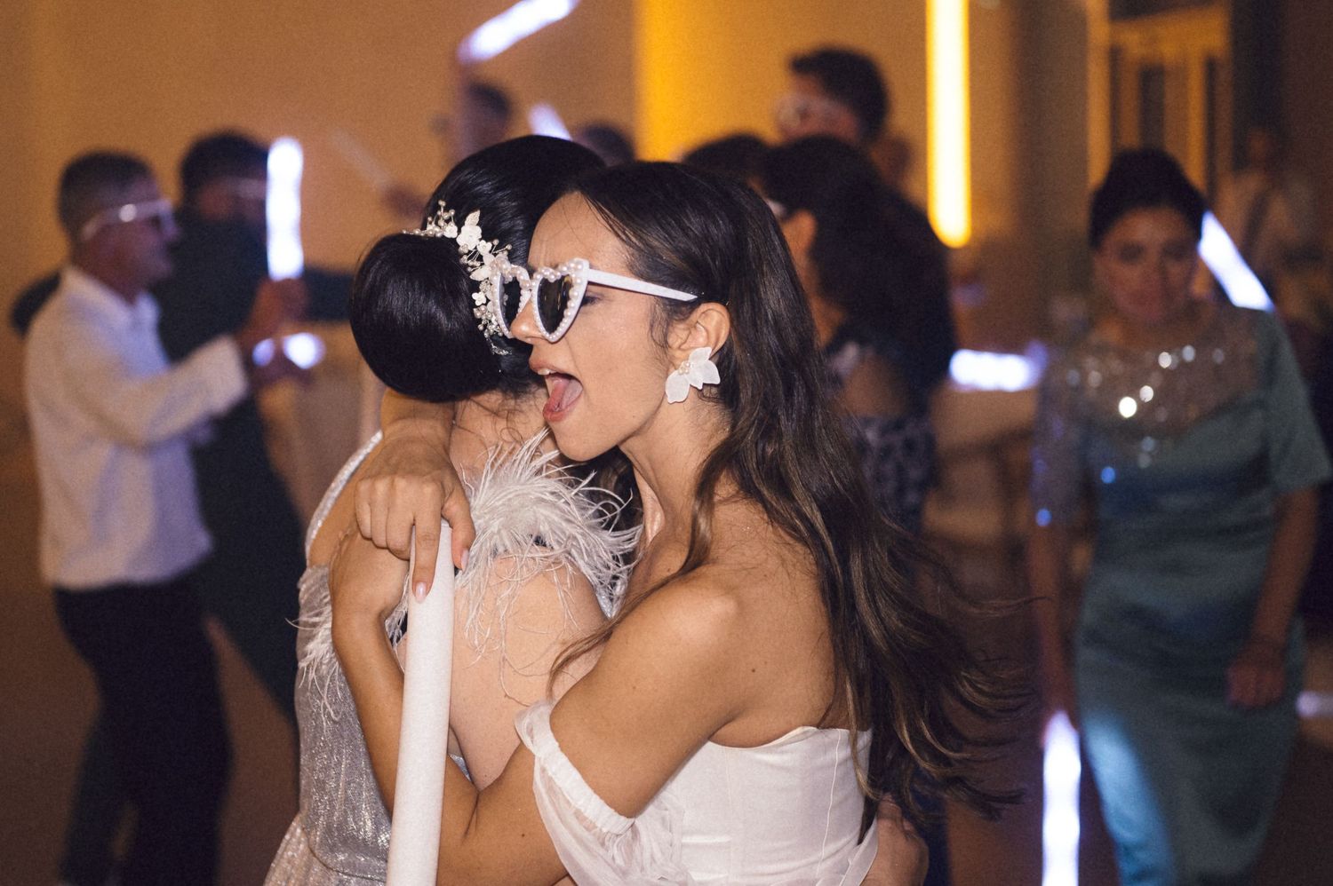Wedding party dancing and celebrating at a reception with warm lighting and festive atmosphere.